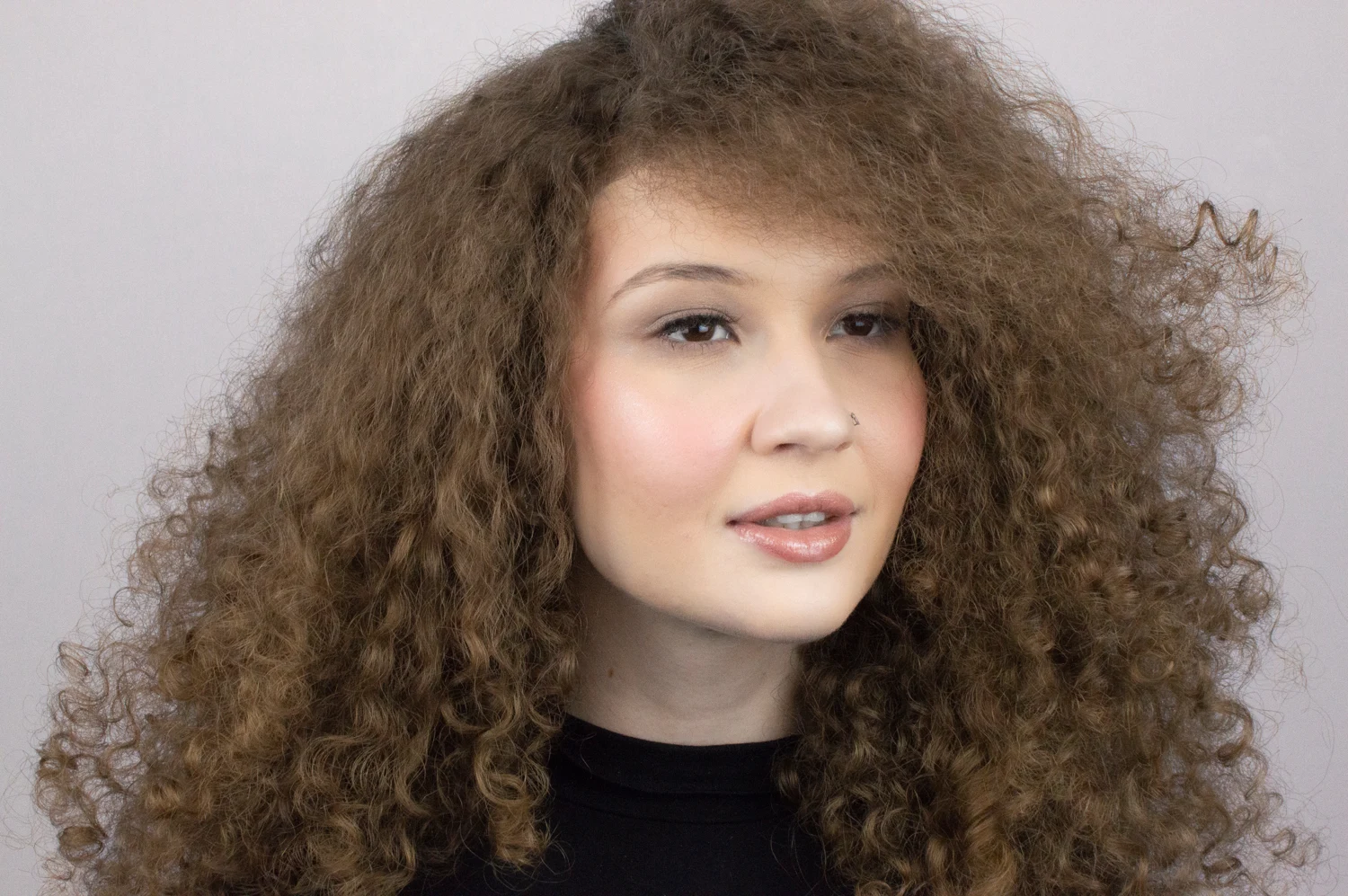 Fashion portrait with curly hair and a natural makeup finish.