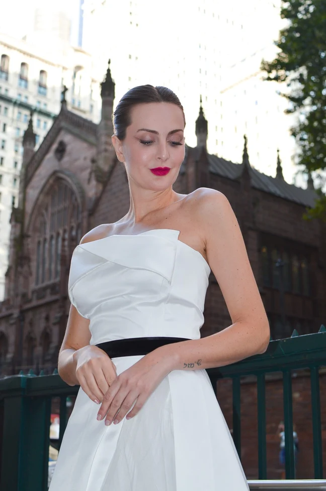 Bride with swept-back hair and a white dress in front of historic architecture.